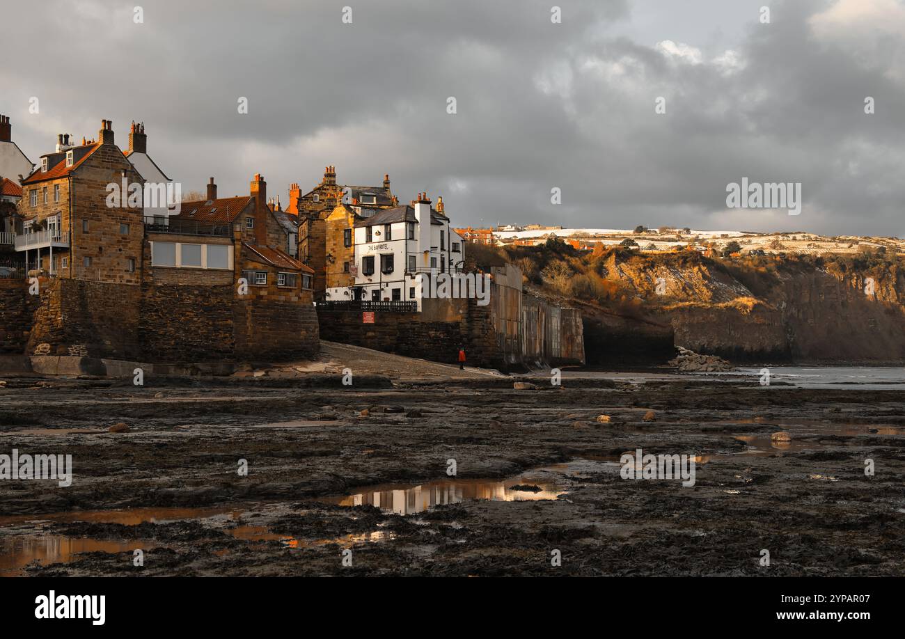 Une brève période de soleil d'hiver illumine les riches couleurs des cottages en pierre et du Bay Hotel à Robin Hoods Bay, Yorkshire Banque D'Images