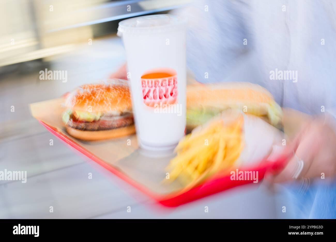 Hanovre, Allemagne. 29 novembre 2024. ILLUSTRATION - Une femme porte un plateau de hamburgers à base de plantes Whopper et long Chicken et des pépites à base de plantes ainsi que des frites et du Coca dans un restaurant de la chaîne de restauration rapide Burger King. Crédit : Julian Stratenschulte/dpa/Alamy Live News Banque D'Images