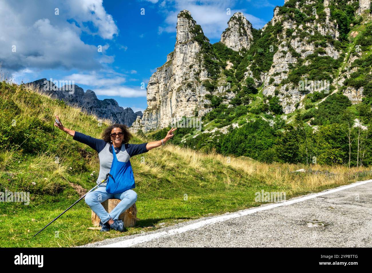 Touriste latino-américain d'âge moyen, souriant, les bras levés dans la joie, se reposant assis pendant une randonnée en montagne. Banque D'Images