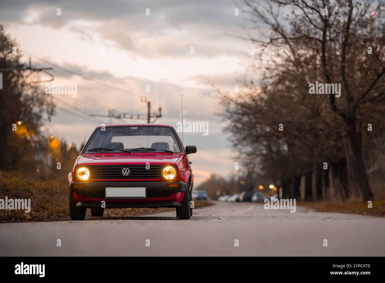 Ljubljana, Slovénie, 29 novembre 2024 : Volkswagen Golf 2 de couleur rouge posant devant le majestueux ciel nocturne et les bâtiments socialistes. Vue frontale Banque D'Images