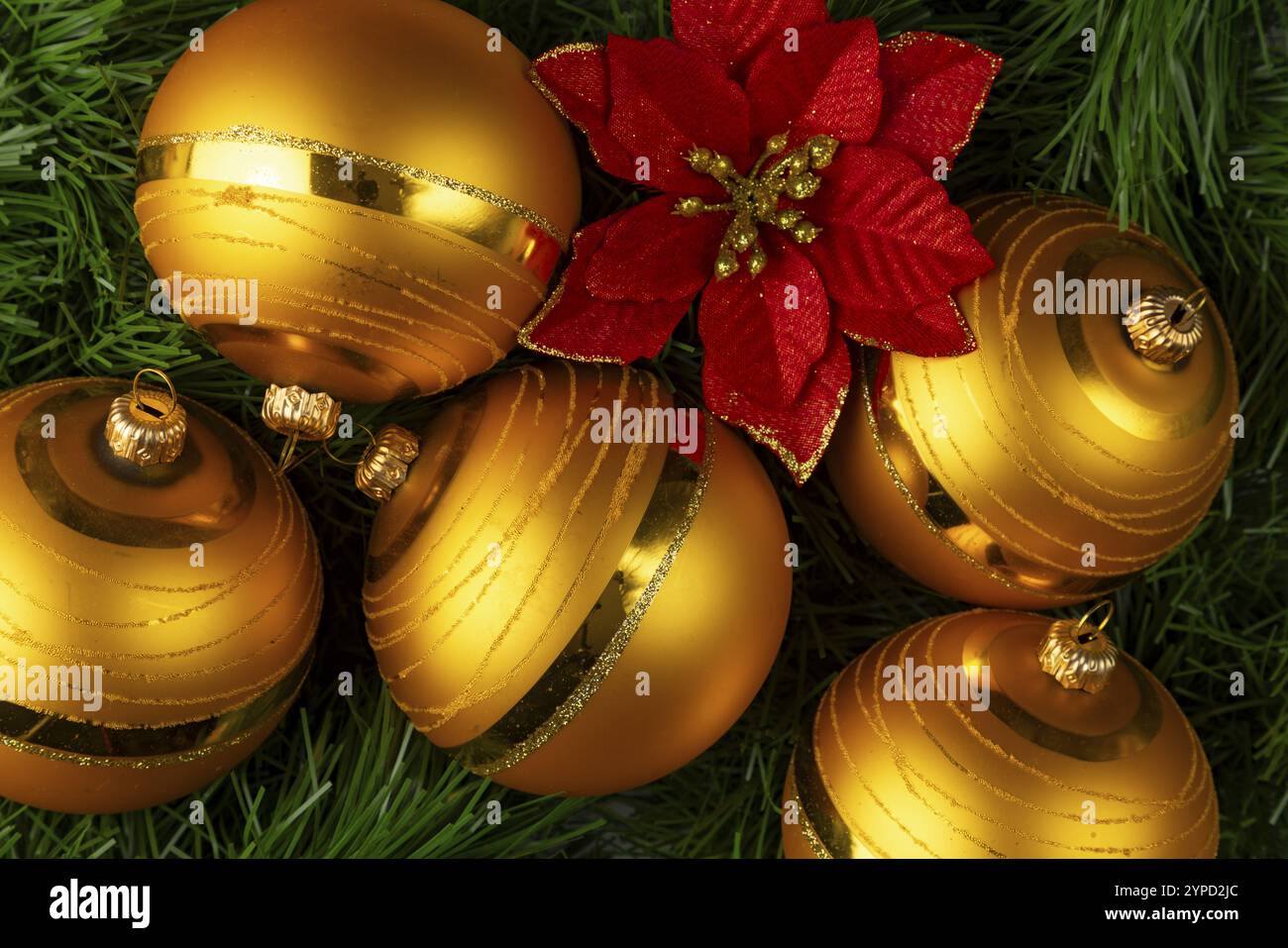 Boules de Noël dorées à côté d'une fleur rouge sur un sapin vert Banque D'Images