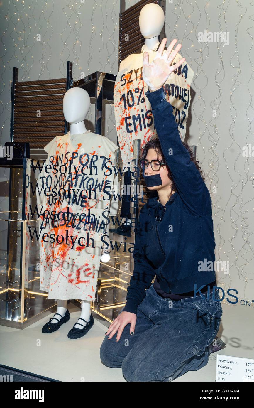 Les écologistes de extinction Rebellion se sont collés à la vitrine du magasin Zara lors du Black Friday pour protester contre le consumérisme qui tue la planète. Personne avec la bouche collée à la vitrine du magasin Zara, mannequins vêtus de bannières : transport à la pollution supplémentaire énorme, mode rapide 10% des émissions mondiales de co2. Varsovie Pologne Copyright : xMikolajxJaneczekx Banque D'Images