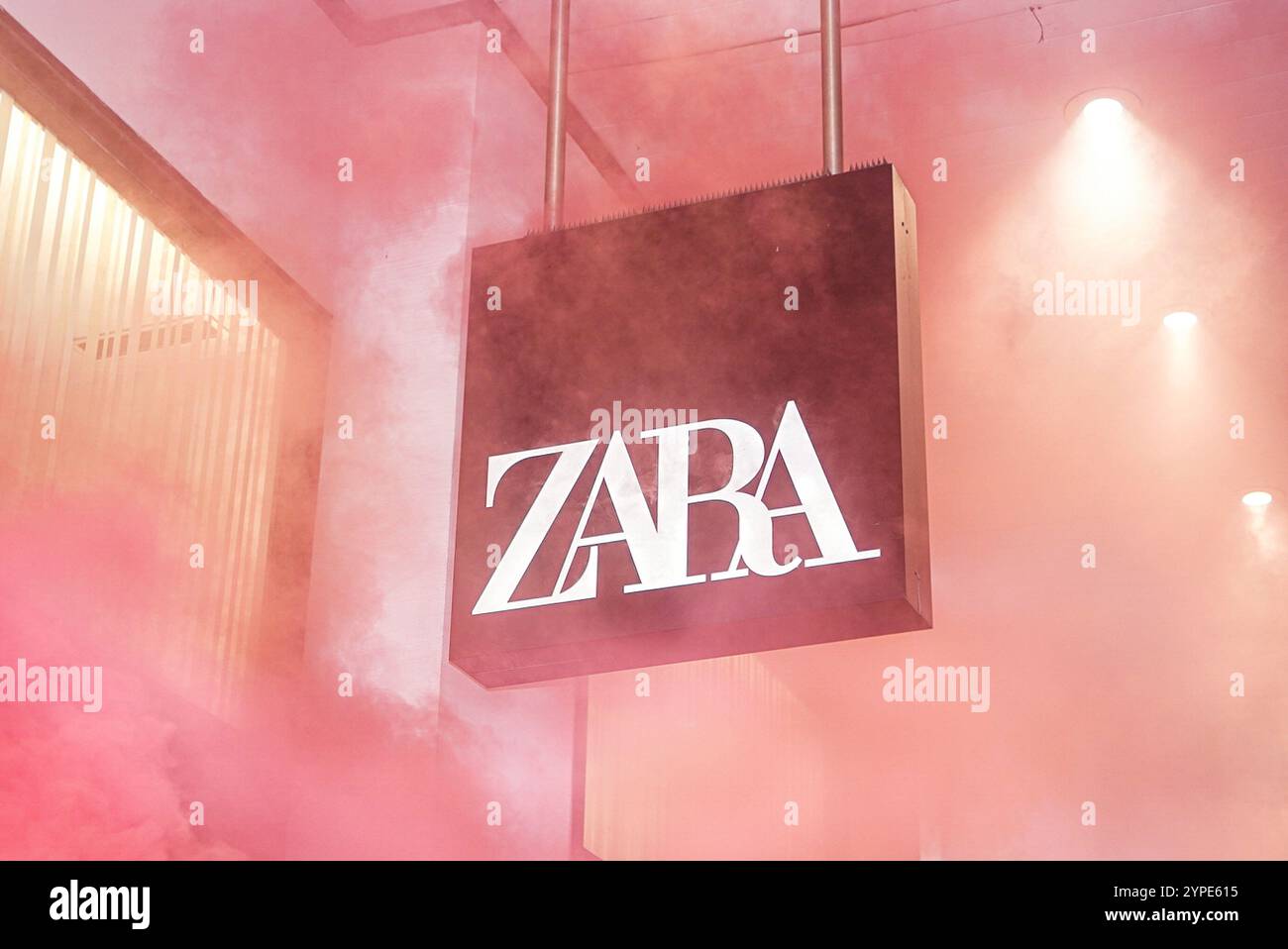 Le logo du magasin Zara entouré de fumée rouge lors d'une démonstration. Le vendredi noir, le 29 novembre, des activistes de extinction Rebellion vêtus de noir de deuil sont descendus dans les rues de Varsovie pour souligner les coûts cachés des grosses réductions et de la manie du shopping. Leur protestation visait à sensibiliser à l’impact destructeur de la consommation excessive, en particulier dans l’industrie de la mode rapide. Le point culminant de l'action a eu lieu lorsque des militants se sont collés à la vitrine de Zara ñ, l'un des symboles de la mode rapide. Utilisant de la colle et des bannières avec des slogans liés au climat, ils ont voulu attirer l'attention Banque D'Images