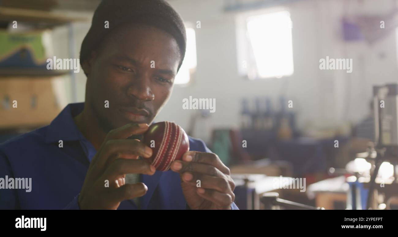 Vue de face gros plan d'un homme afro-américain travaillant dans l'atelier d'une usine fabriquant du cricket B. Banque D'Images