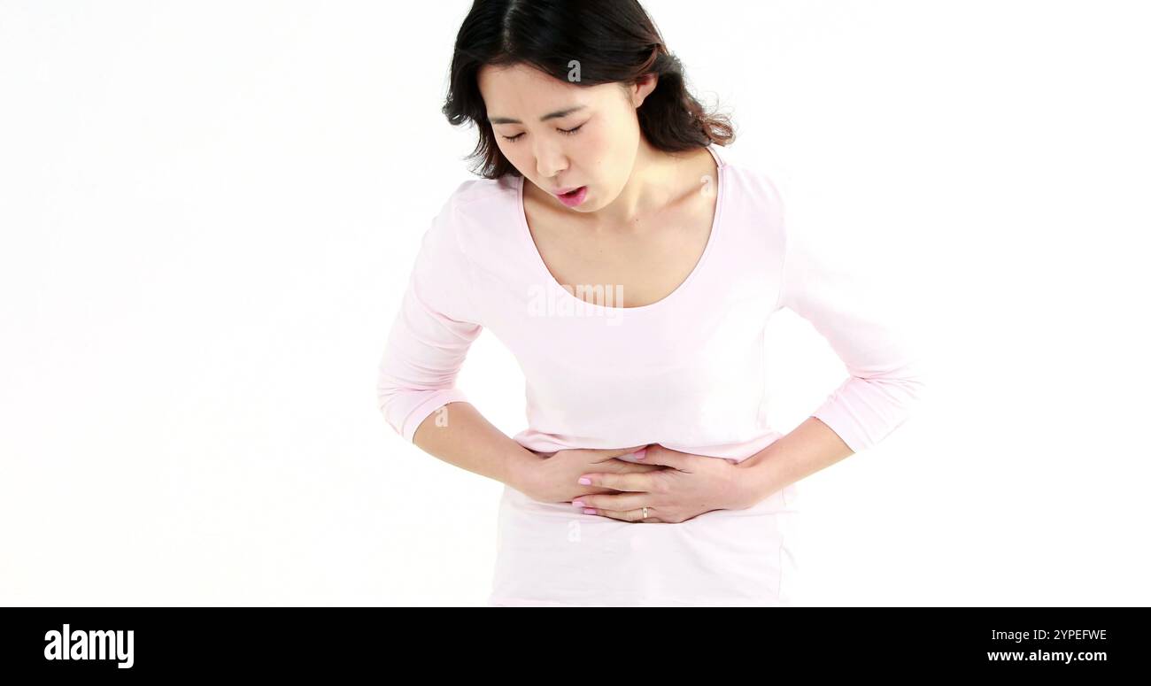 Jolie femme asiatique avec mal d'estomac sur écran blanc Banque D'Images