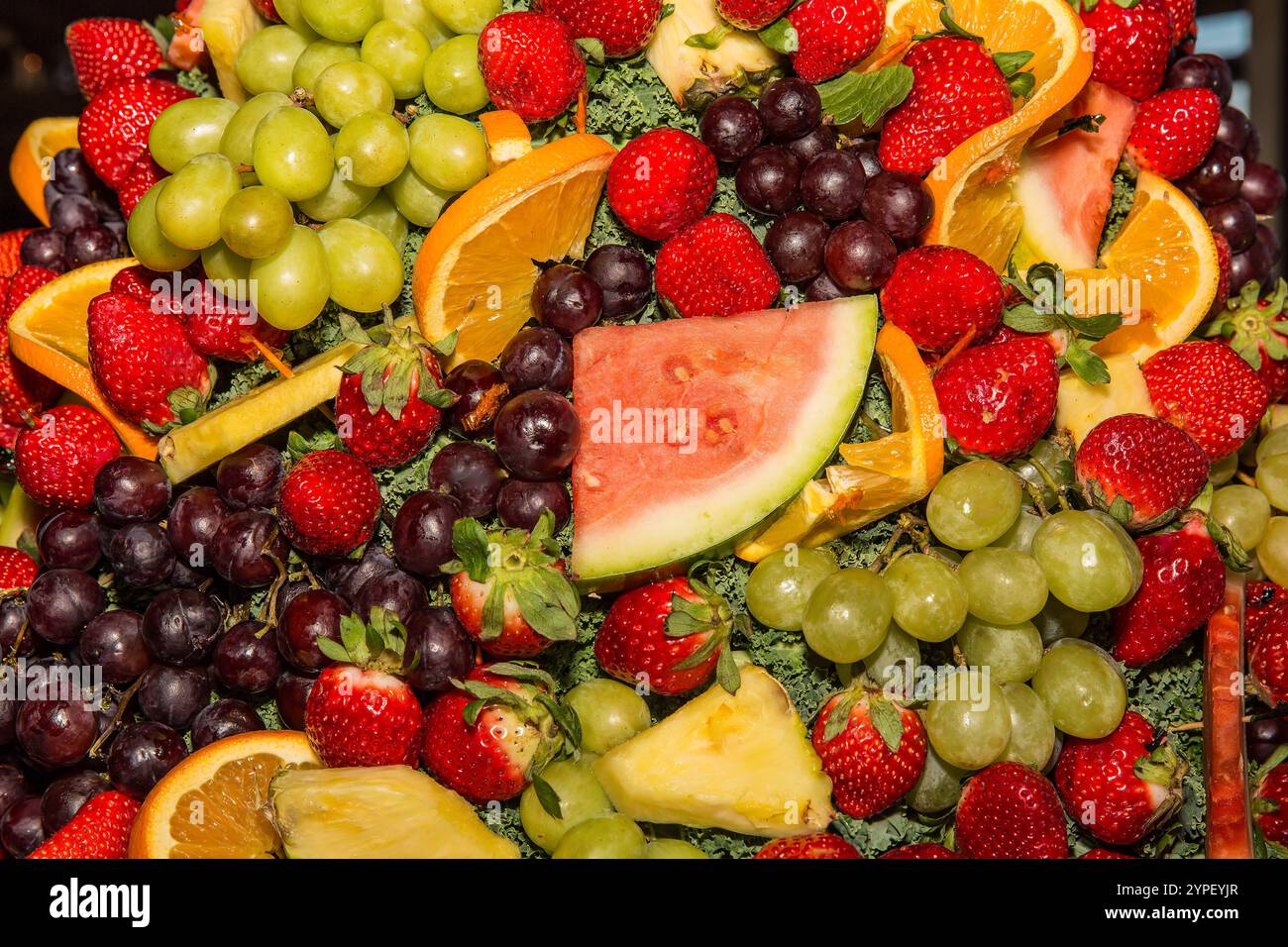 Fond de fruits coloré avec fraises, raisins, ananas, oranges et melon - mélange frais et juteux Banque D'Images