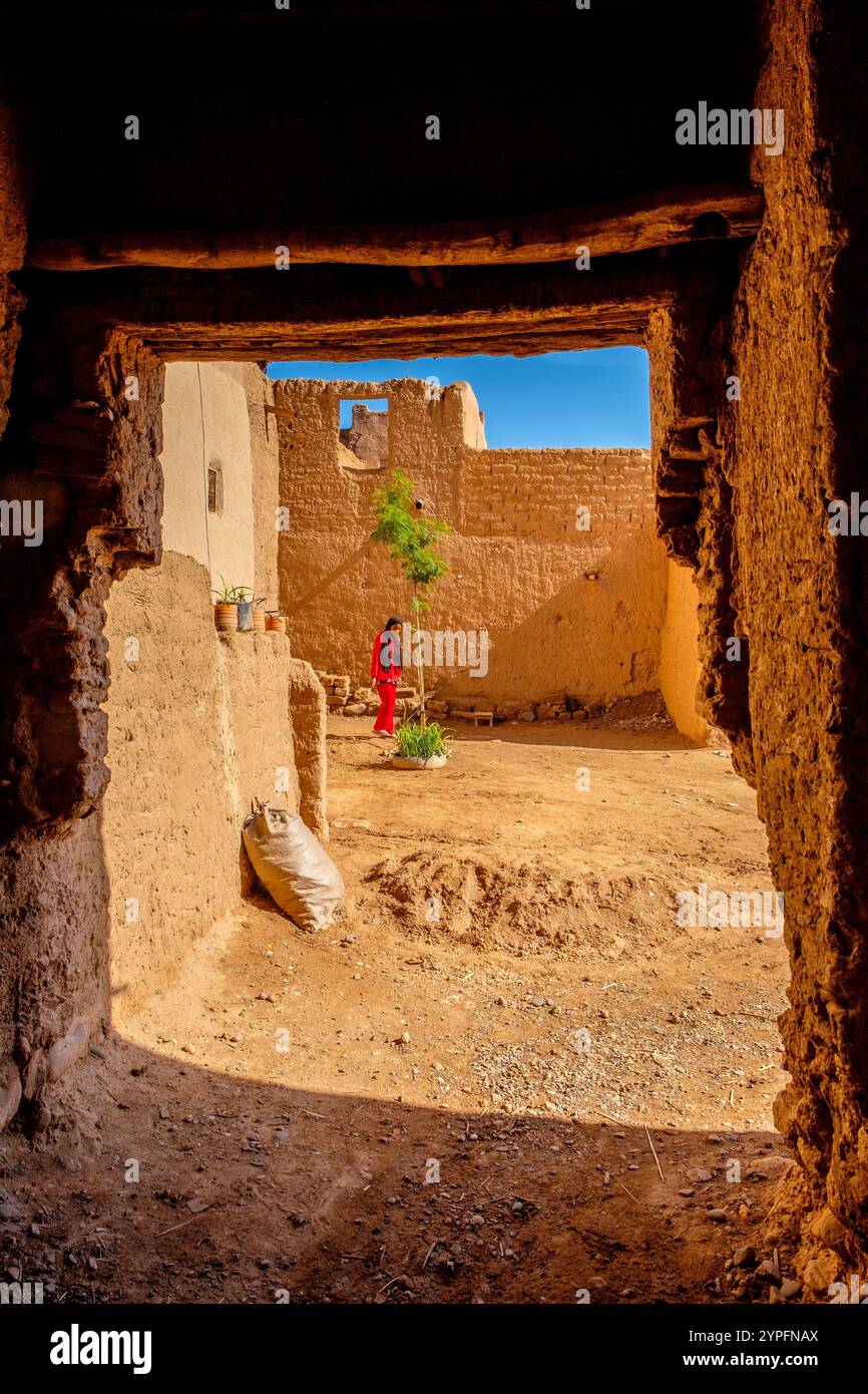 Une jeune fille marocaine dans la cour d'une maison traditionnelle de pise / Kasbah dans la vallée du Draa, Maroc Banque D'Images