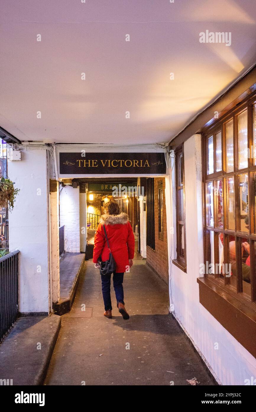 Femme en manteau rouge marchant le long des rangées dans la ville de Cheshire de Chester Banque D'Images