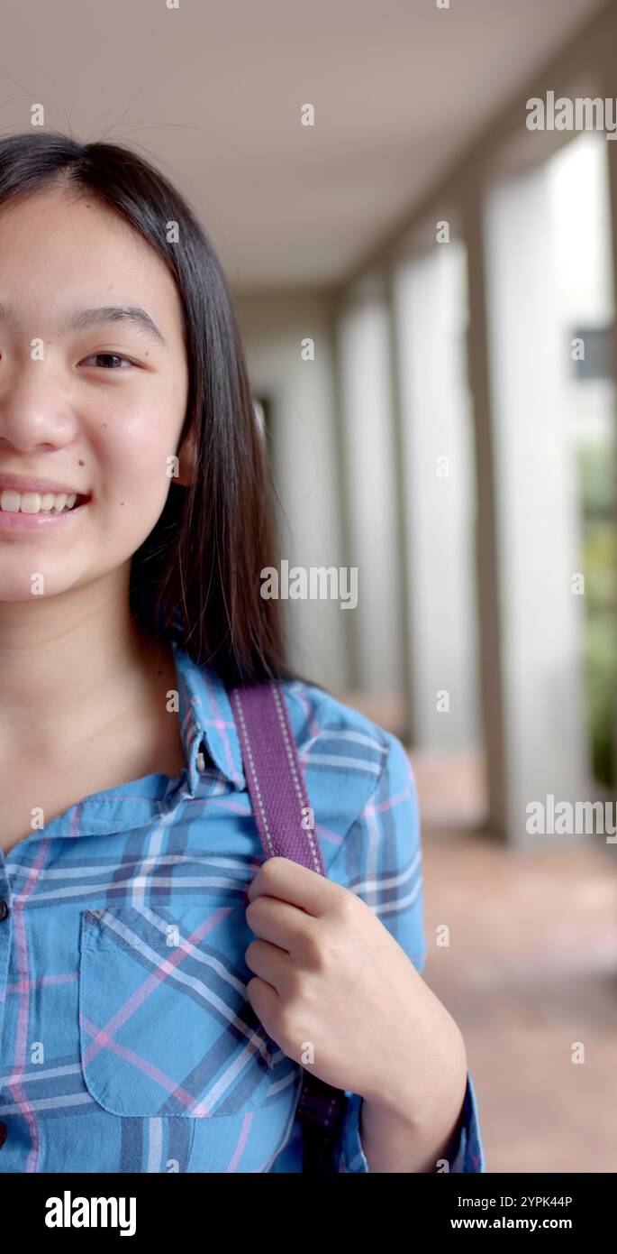 Image verticale : au lycée, une jeune étudiante asiatique sourit Banque D'Images