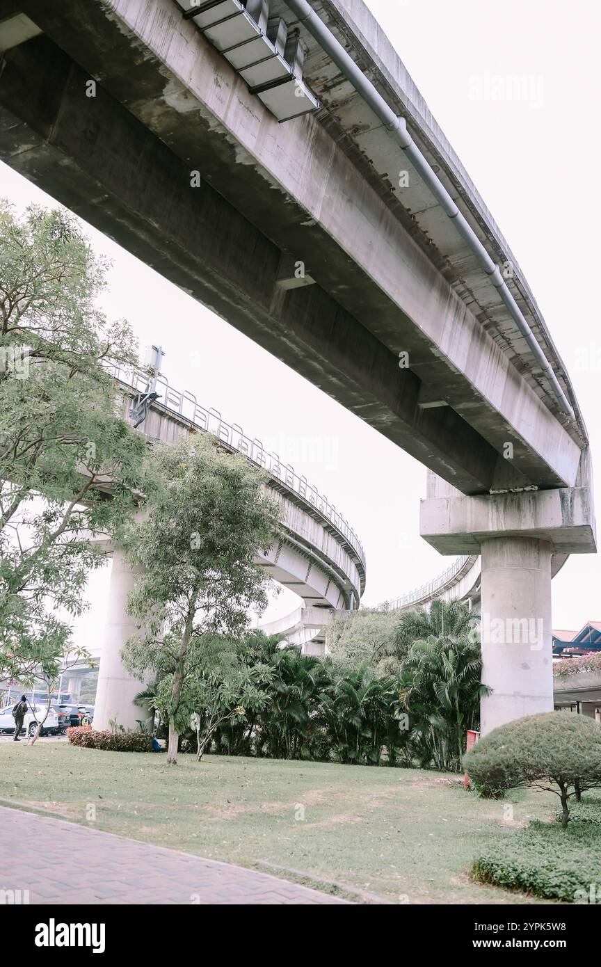 Traversée de voie MRT au-dessus d'une passerelle piétonne, offrant une vue unique sur le transport urbain croisant la vie quotidienne sur la rue ci-dessous Banque D'Images