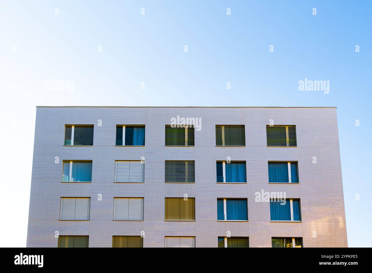 Bâtiment résidentiel minimaliste avec façade blanche propre et fenêtres symétriques sous un ciel clair Banque D'Images