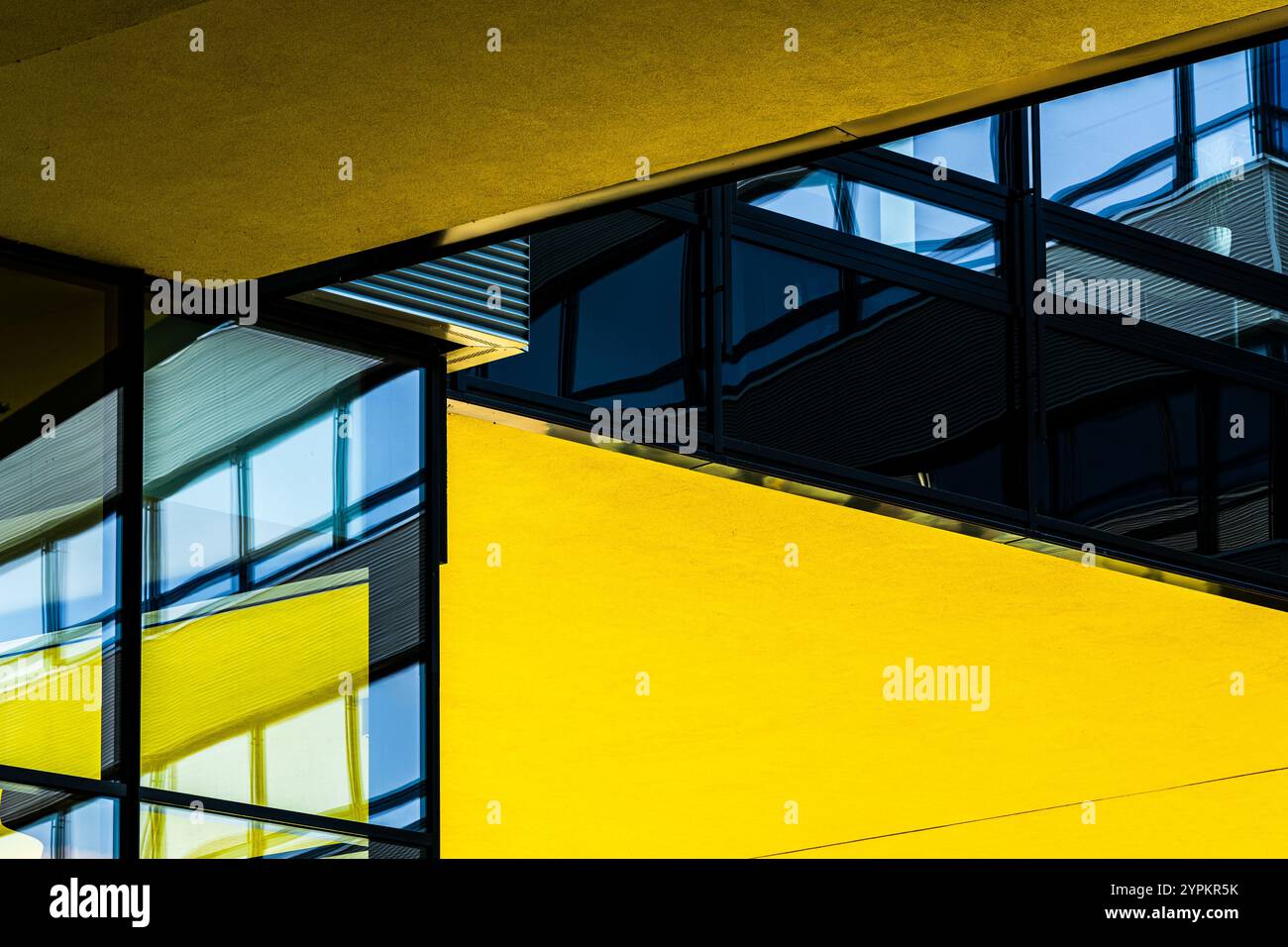 Vue abstraite de l'architecture moderne avec des murs jaune gras et des panneaux de verre réfléchissants Banque D'Images