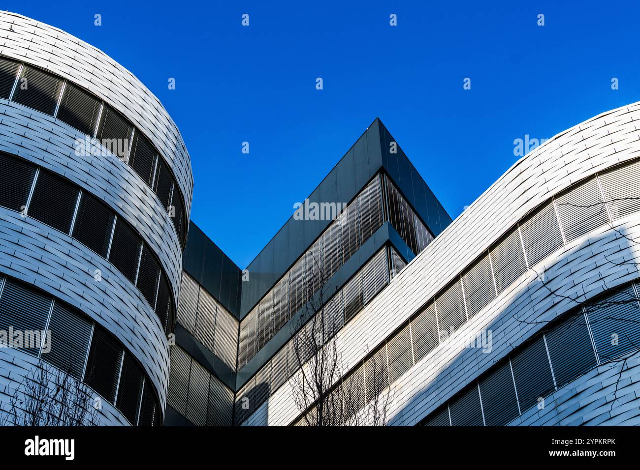 Design architectural moderne avec façades courbes et angulaires contre un ciel bleu lumineux Banque D'Images