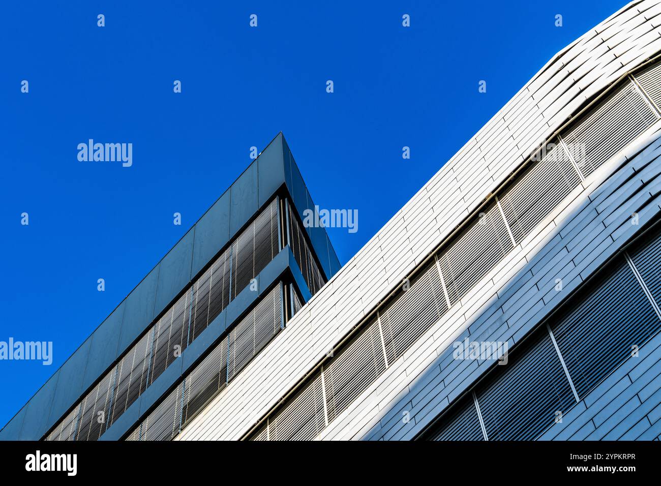 Design architectural moderne avec façades courbes et angulaires contre un ciel bleu lumineux Banque D'Images