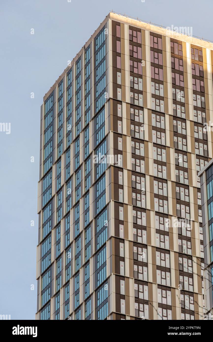 Façade moderne d'immeuble d'appartements à Canary Wharf avec motifs géométriques de fenêtres en verre et revêtement beige sur ciel dégagé Banque D'Images