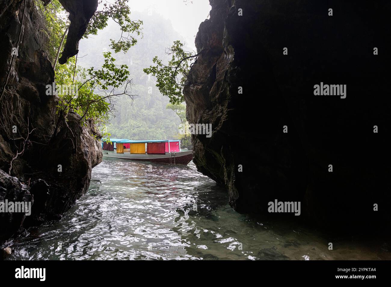 Bateau de pêche traditionnel en bois de couleur blanche à l'entrée d'une grotte marine, jour de pluie, archipel de sombori, sulawesi, indonésie Banque D'Images
