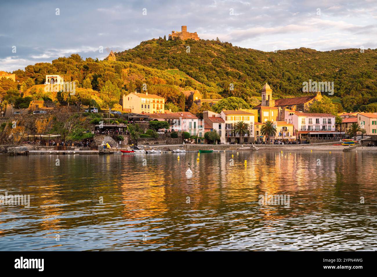 Hôtels, bars et restaurants sur la promenade de la plage de Collioure en contrebas du Fort Saint-Elme illuminé par le coucher du soleil, Languedoc-Roussillion, France Banque D'Images