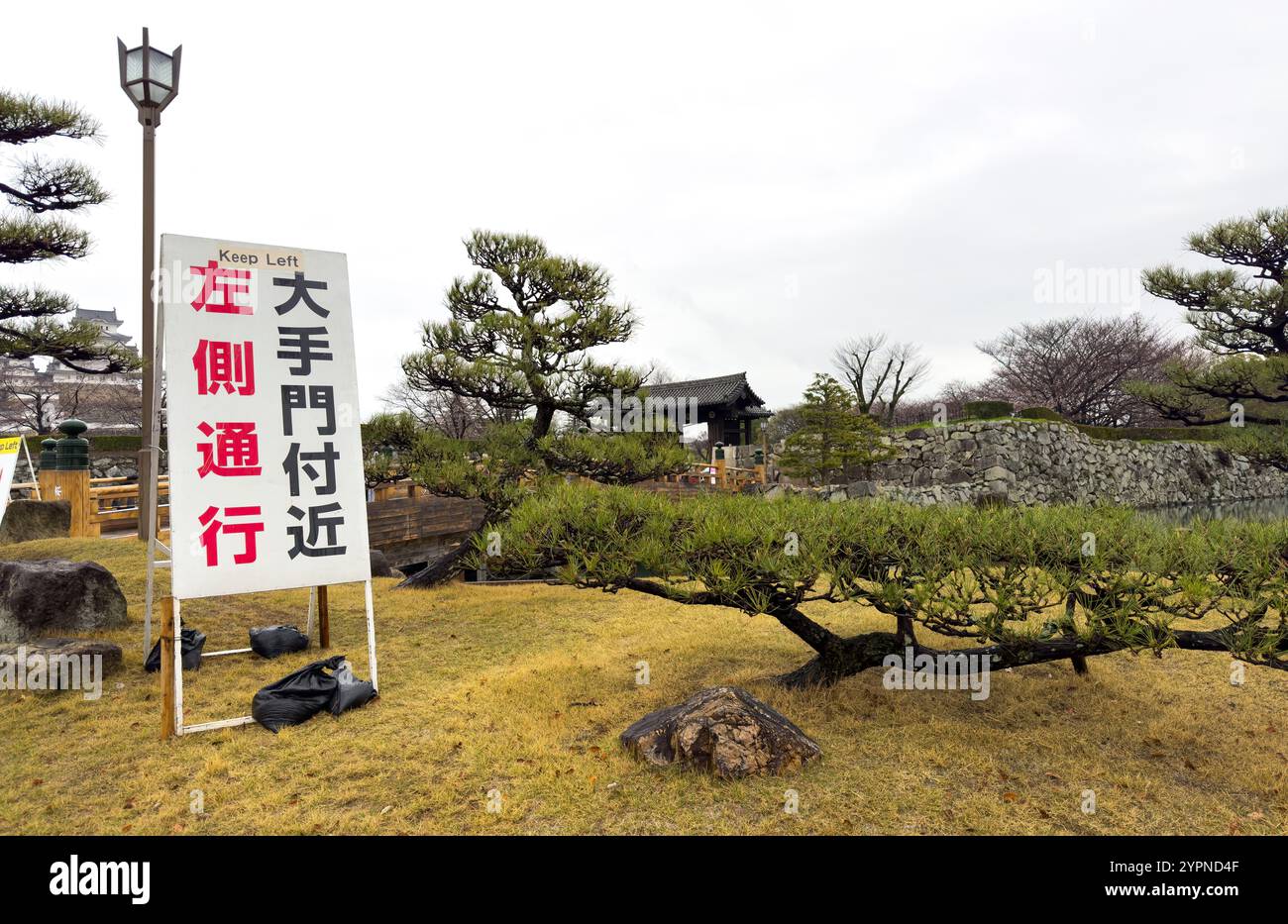 Marchez sur le côté gauche, restez à gauche. Texte de signe en japonais et anglais à l'entrée du château blanc de Himeji, Japon. Banque D'Images