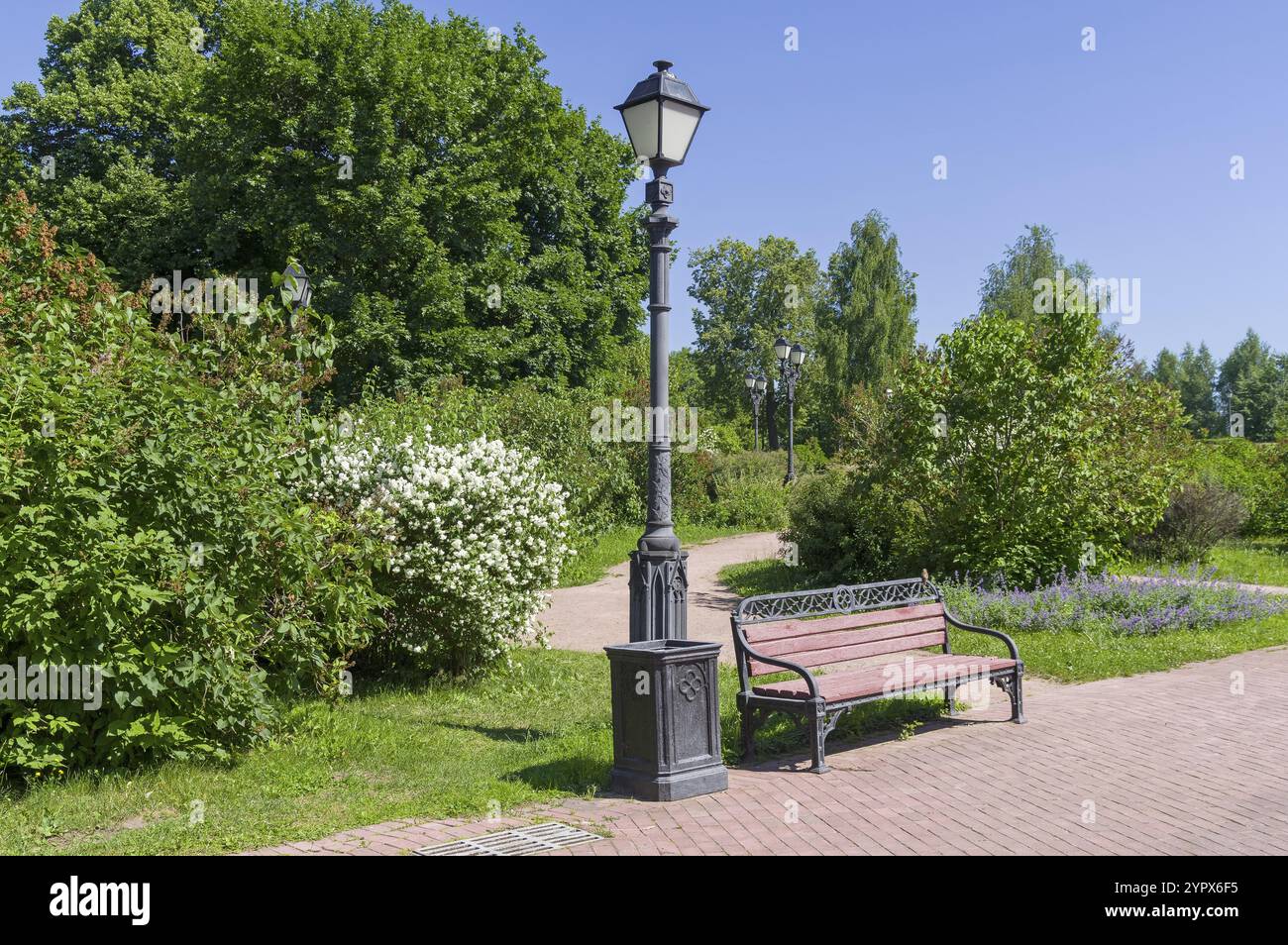 Un coin confortable dans le parc, une lanterne, un banc et un buisson orangé en fleurs. Parc Tsaritsynski, Moscou, Russie. Journée ensoleillée en juin Banque D'Images