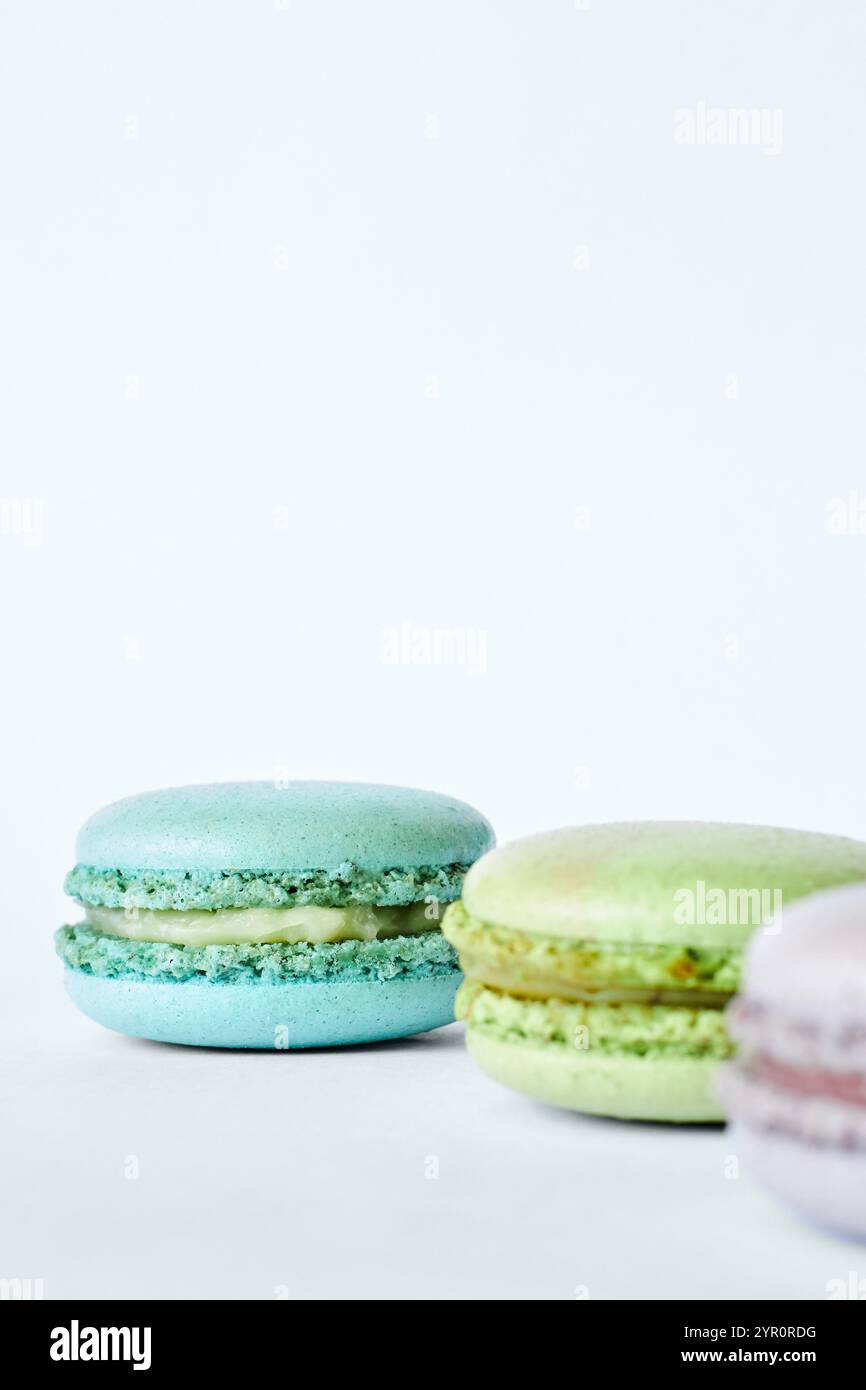 Trois macarons français colorés sur fond gris, des gâteaux aux saveurs différentes, menthe, pomme, saveur de groseille. Dessert maison, macarons aigue-marine, Banque D'Images