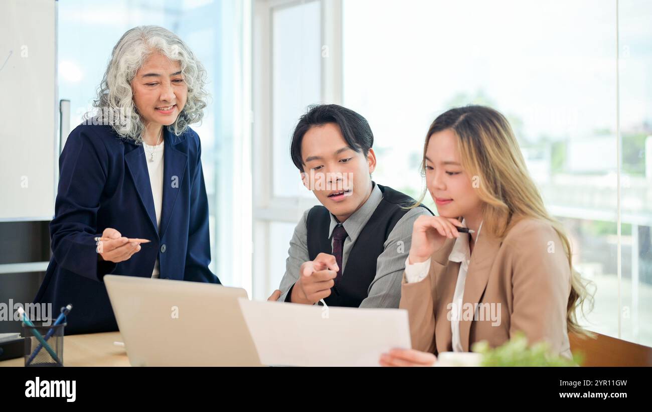 Un homme d'affaires asiatique professionnel et intelligent dans un costume formel partage en toute confiance ses idées et explique un projet à son équipe lors d'une busine collaborative Banque D'Images