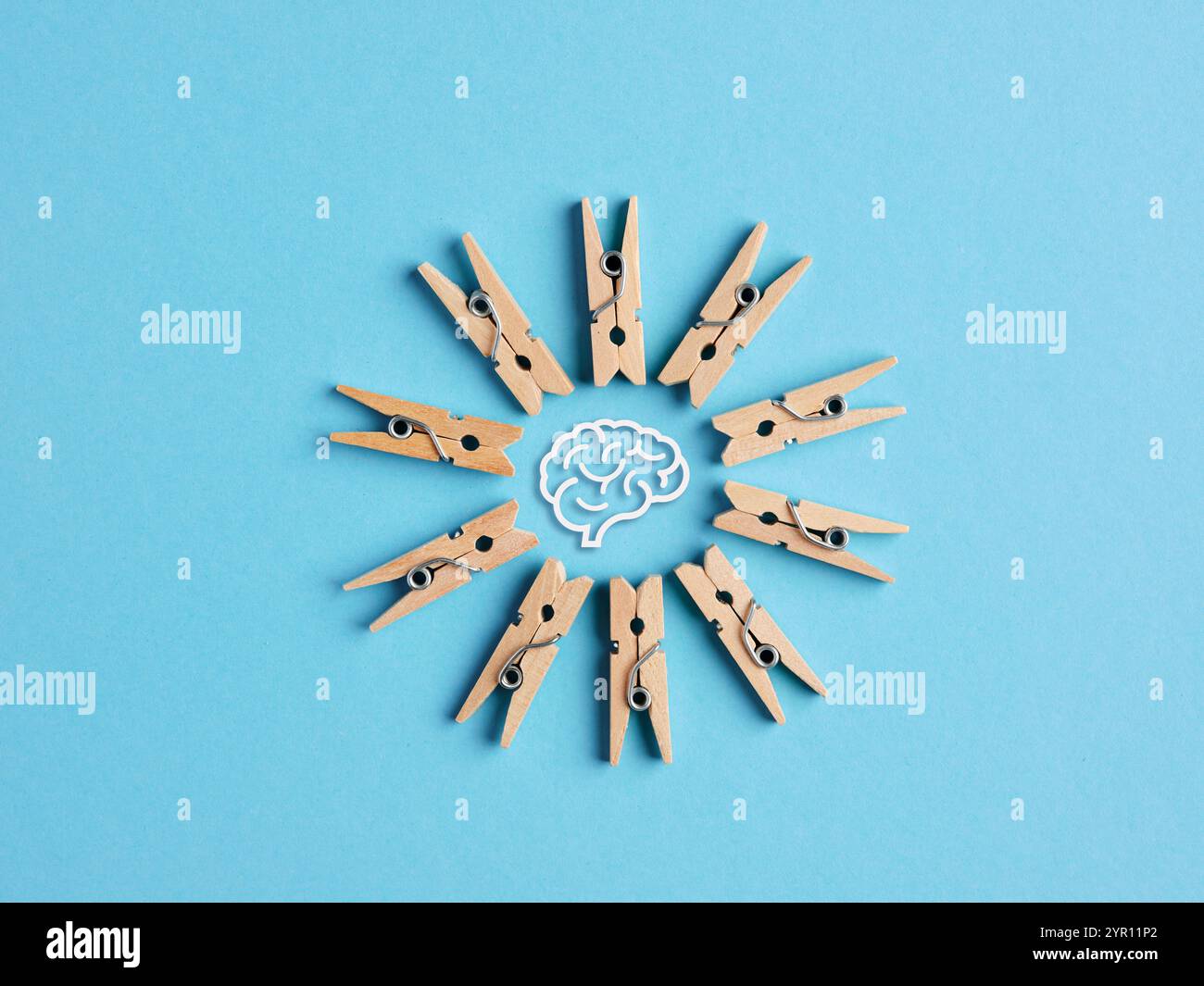 Pensée collective et concept de brainstorming. Pinces à linge miniatures en bois formant un cadre circulaire avec le symbole du cerveau humain sur fond bleu. Banque D'Images