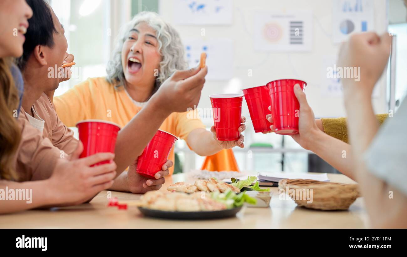 Les employés asiatiques souriants et joyeux apprécient les boissons et les conversations tout en célébrant leur projet réussi lors d'une fête de bureau. renforcement de l'esprit d'équipe, Banque D'Images