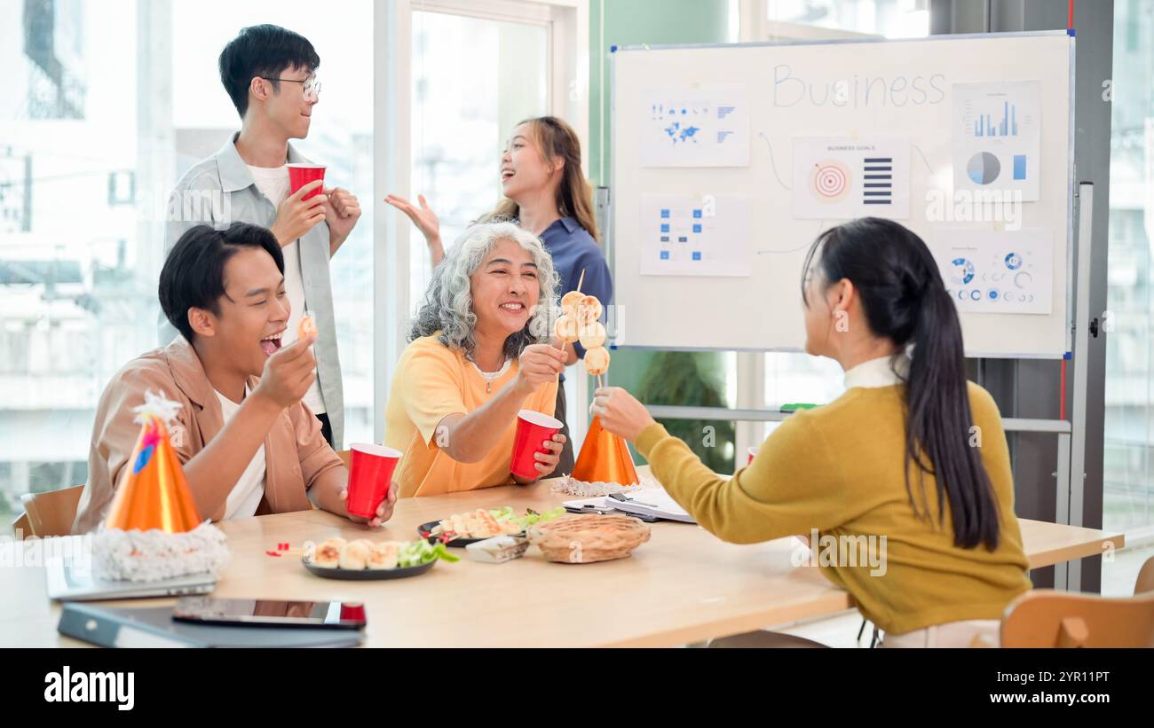 Les employés asiatiques souriants et joyeux apprécient les boissons et les conversations tout en célébrant leur projet réussi lors d'une fête de bureau. renforcement de l'esprit d'équipe, Banque D'Images