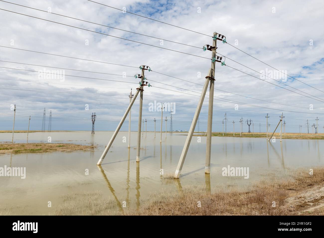 Les poteaux électriques s'élèvent des champs gorgés d'eau, leurs bases submergées, tandis que le ciel couvert se dessine au-dessus du ciel dans une zone rurale Banque D'Images