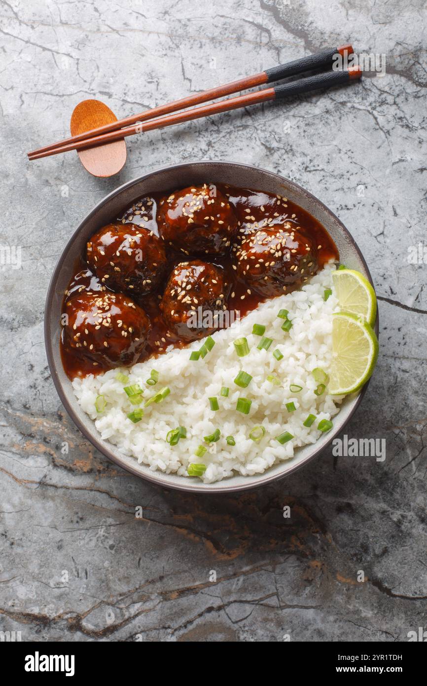 Boulettes de viande sriracha au miel collant avec du riz en gros plan sur le bol sur la table. Vue de dessus verticale Banque D'Images