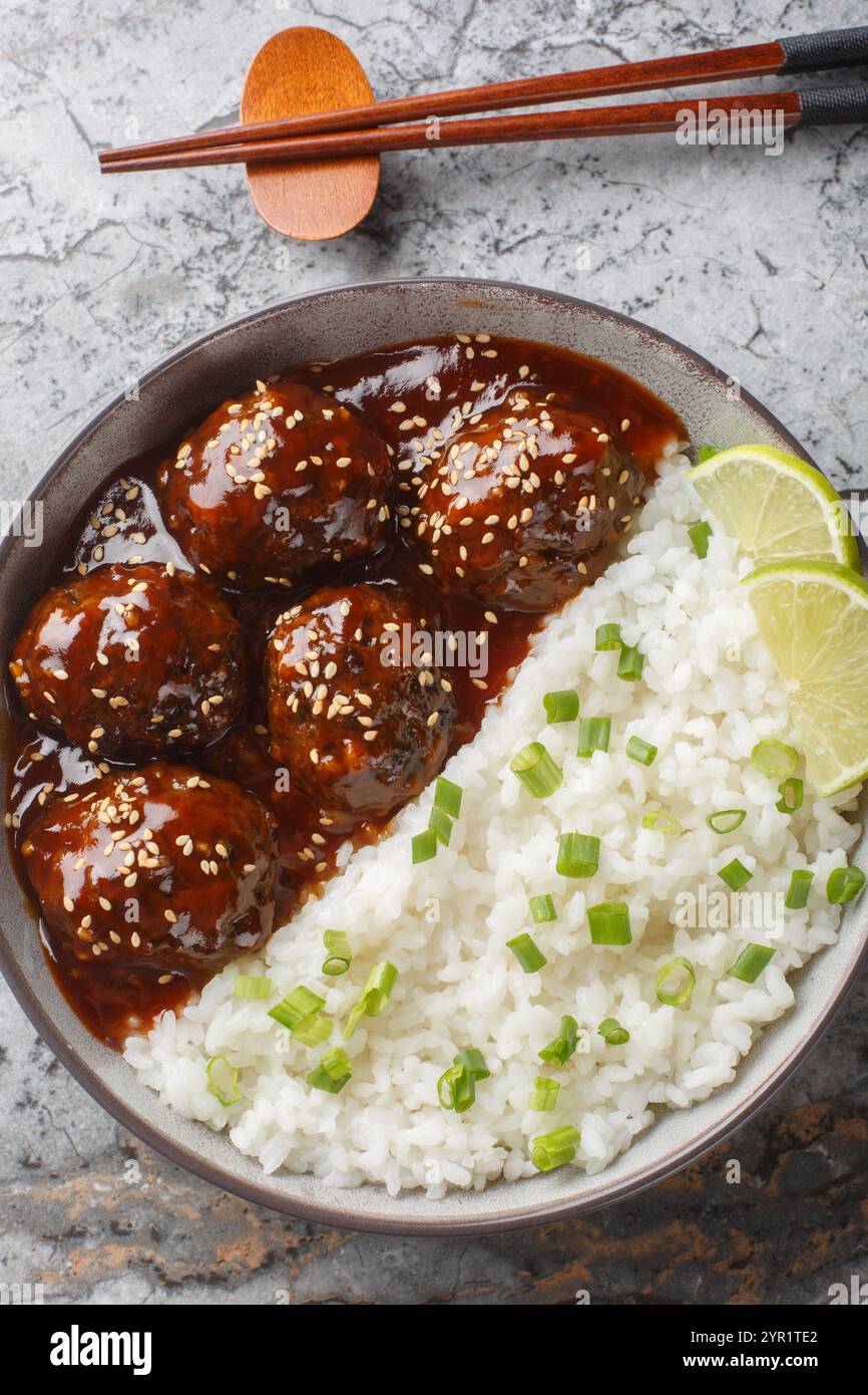 Asian Honey Sriracha Meatballs avec riz gros plan sur le bol sur la table. Vue de dessus verticale Banque D'Images