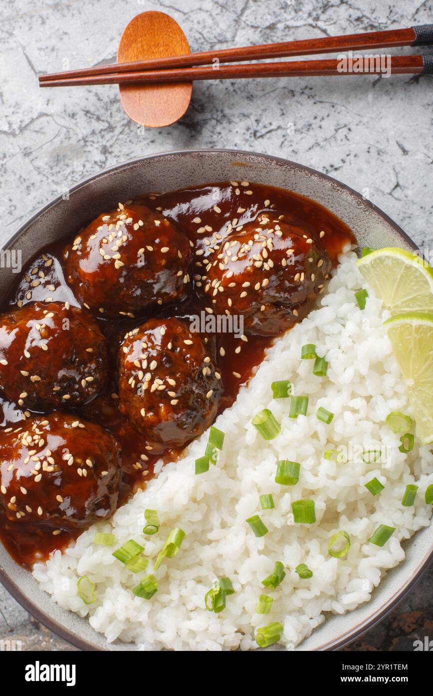 Boulettes de viande sucrées et épicées en sauce sriracha au miel servies avec du riz gros plan dans un bol sur une table. Vue de dessus verticale Banque D'Images