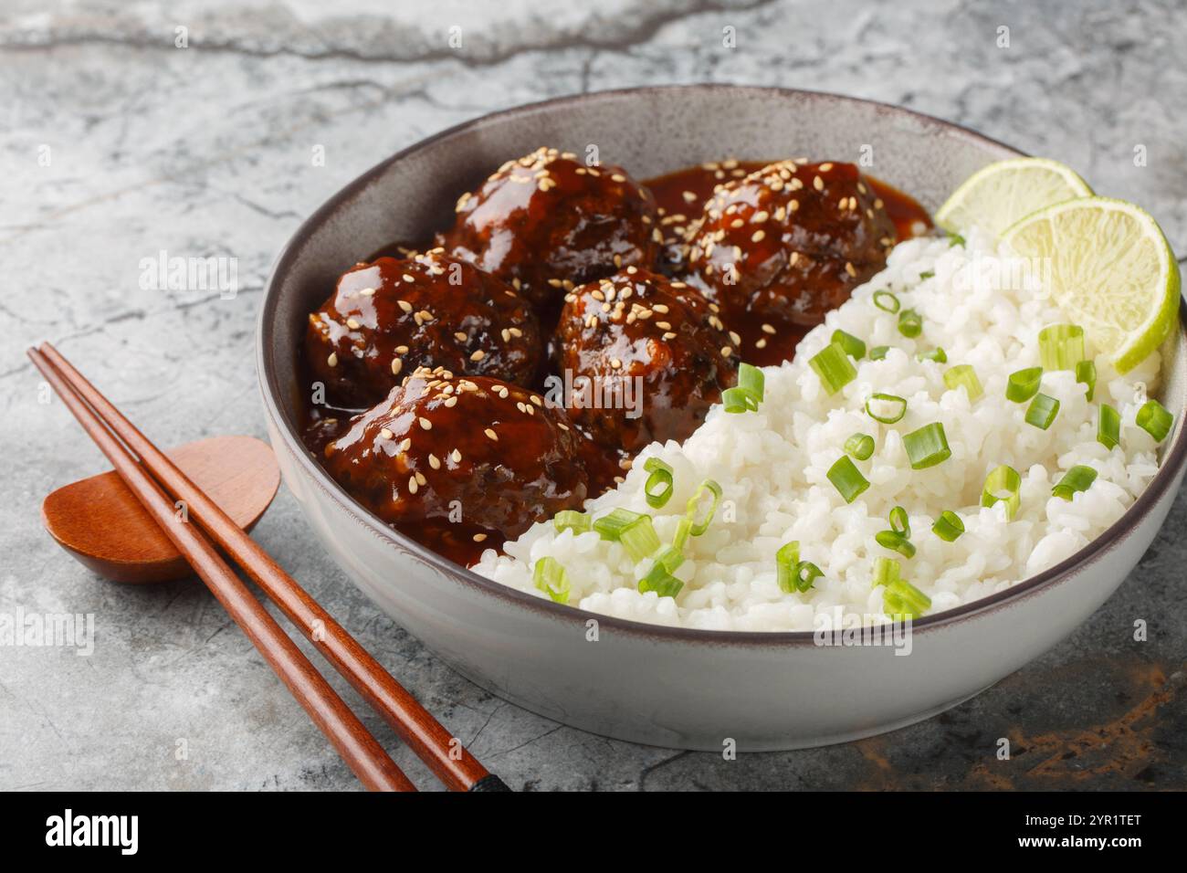 Boulettes de viande glacées à la sauce sriracha au miel servies avec du riz gros plan dans un bol sur une table. horizontal Banque D'Images