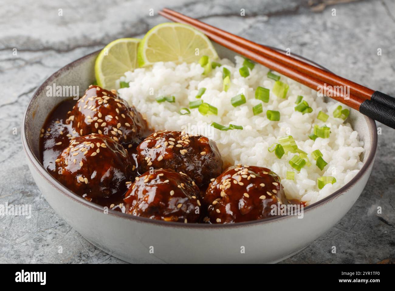 Boule de viande glacée au miel Sriracha servie avec du riz en gros plan sur le bol sur la table. Horizontal Banque D'Images
