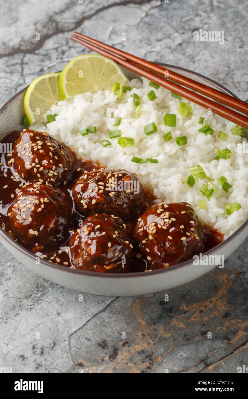 Boulettes de viande sriracha au miel collant avec du riz en gros plan sur le bol sur la table. Vertical Banque D'Images