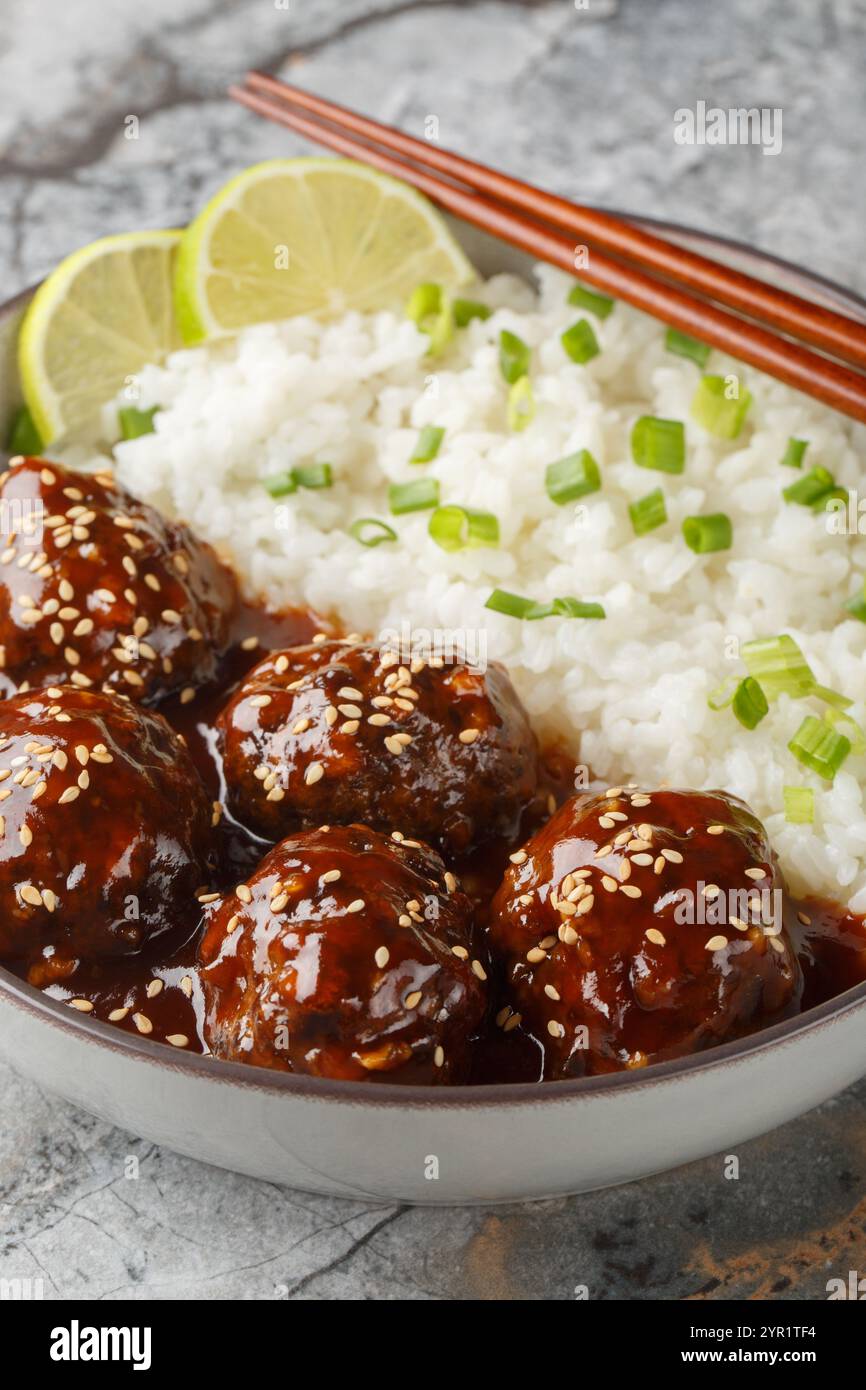 Boulettes de viande sucrées et épicées en sauce sriracha au miel servies avec du riz gros plan dans un bol sur une table. Vertical Banque D'Images