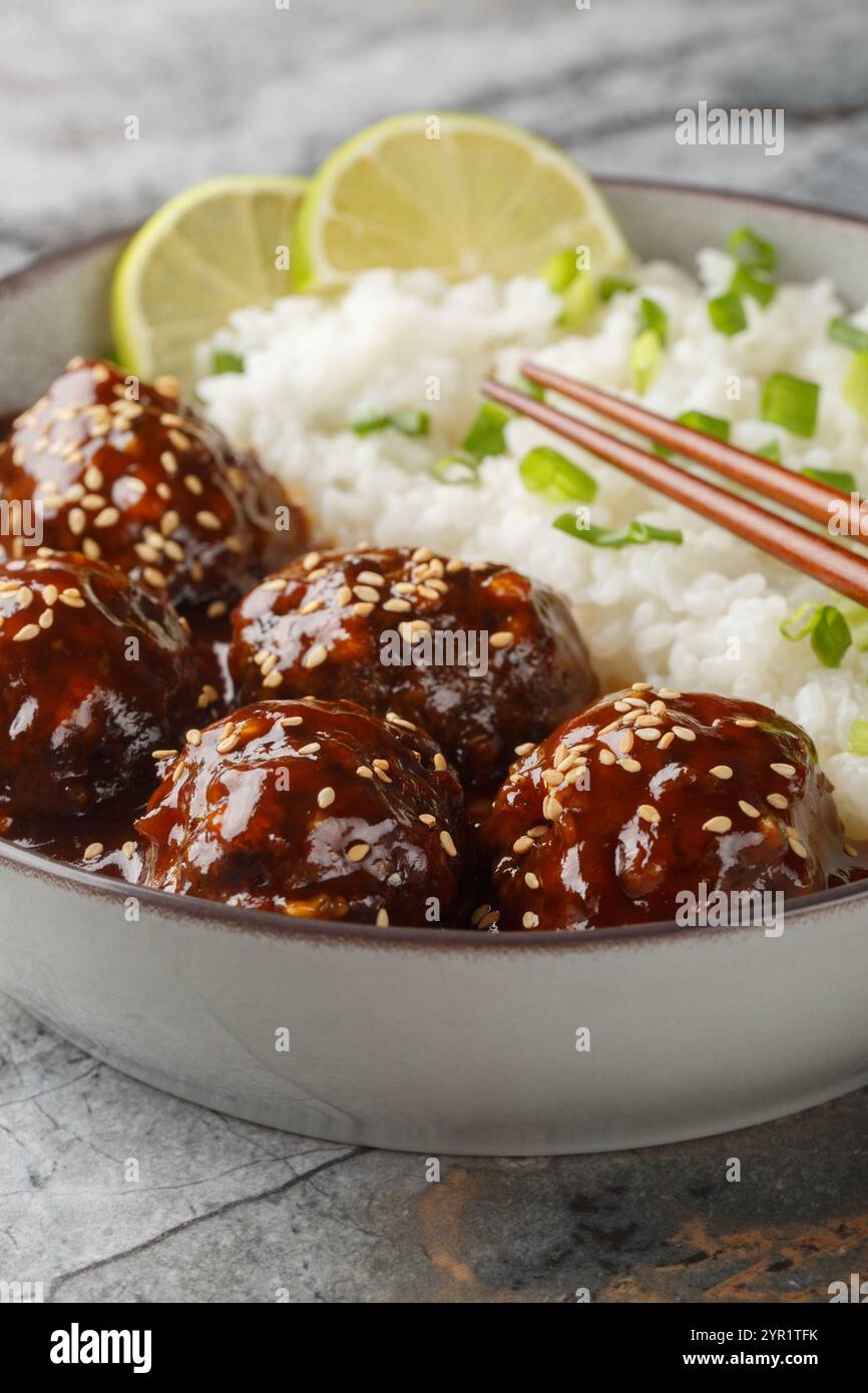 Asian Honey Sriracha Meatballs avec riz gros plan sur le bol sur la table. Vertical Banque D'Images