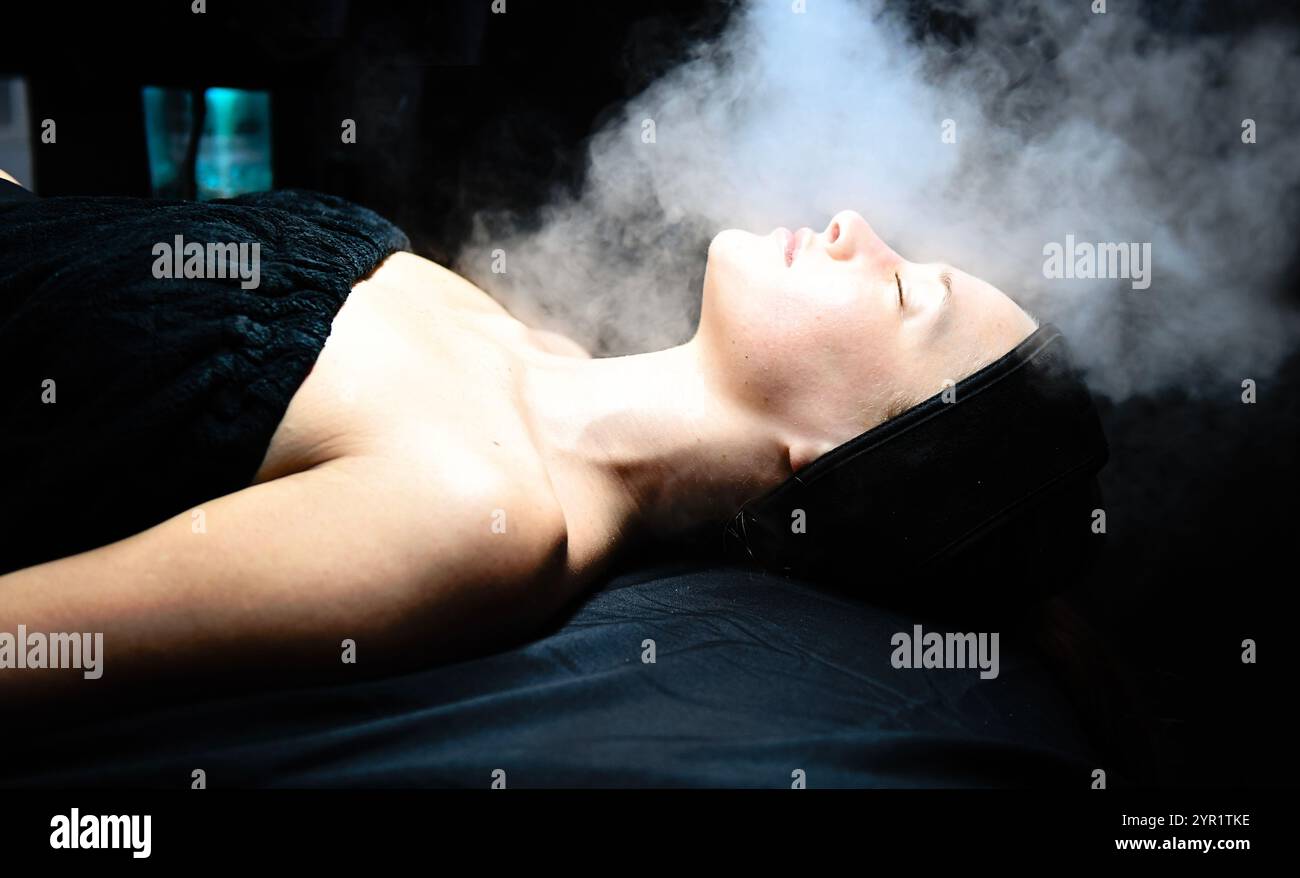 Une femme subissant un traitement facial à la vapeur dans un environnement thermal Banque D'Images