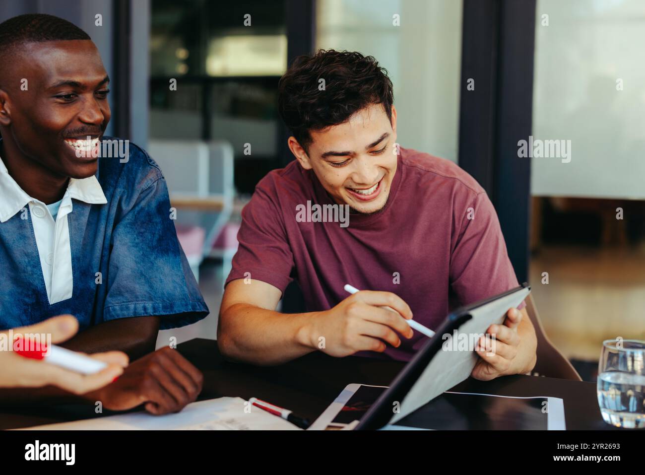 Étudiants de niveau collégial utilisant la technologie pour l'apprentissage collaboratif, s'engageant dans une session d'étude productive avec une tablette numérique dans un ensemble éducatif moderne Banque D'Images