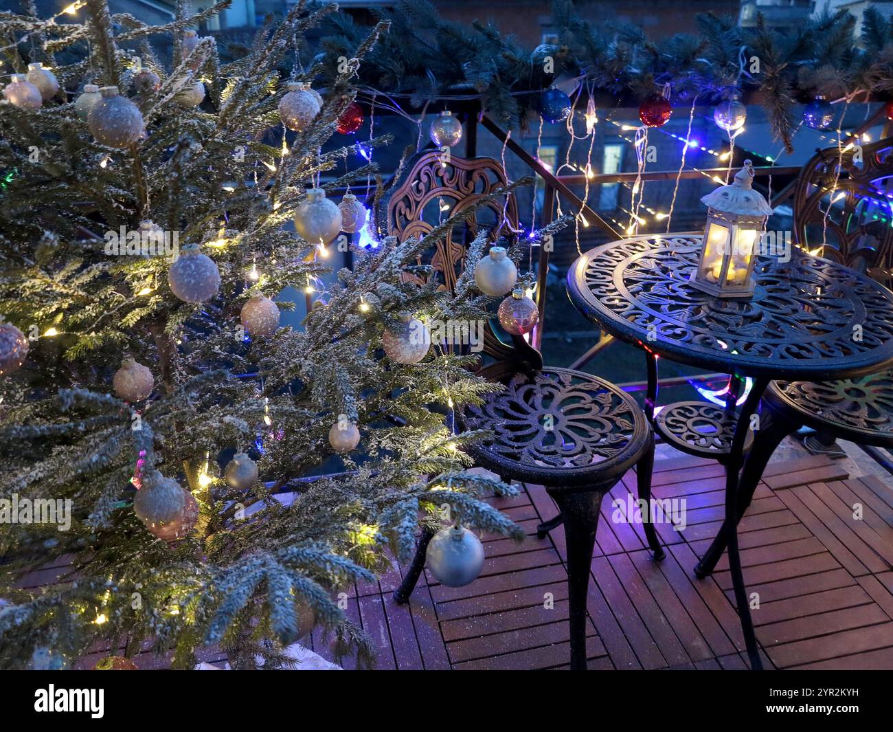 Un balcon confortable décoré pour Noël, avec un arbre lumineux orné d'ornements et de lumières scintillantes. Guirlandes festives, lanternes et scintillants Banque D'Images