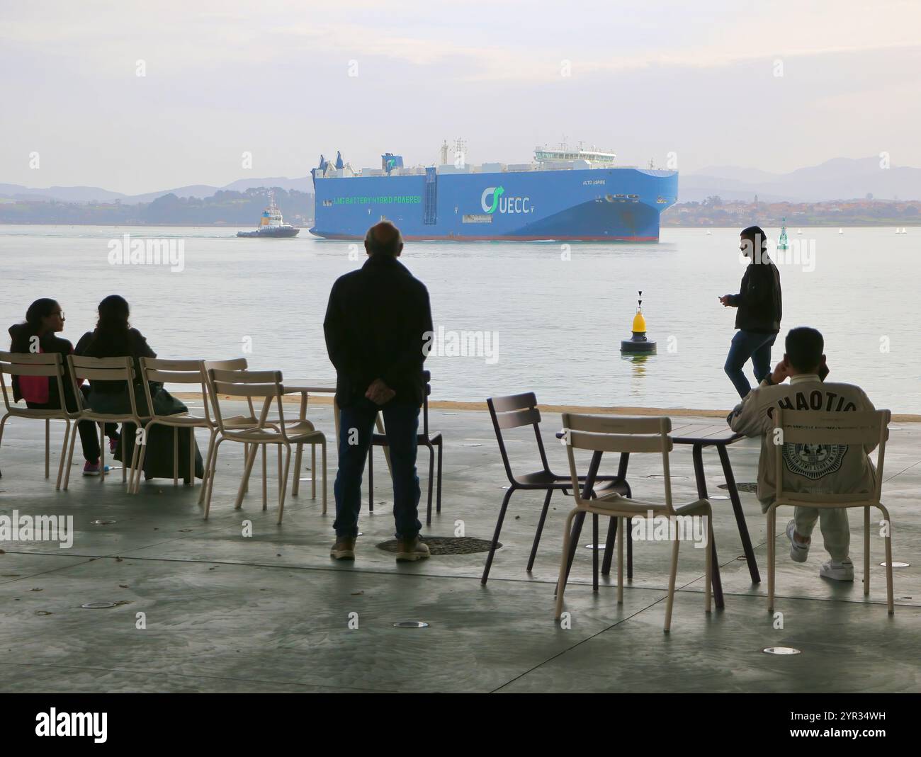 Les gens regardant d'une terrasse l'arrivée des véhicules transporteur navire Auto Aspire au port avec remorqueur Trheintaycuatro Botin Centre Santander Bay Espagne Banque D'Images