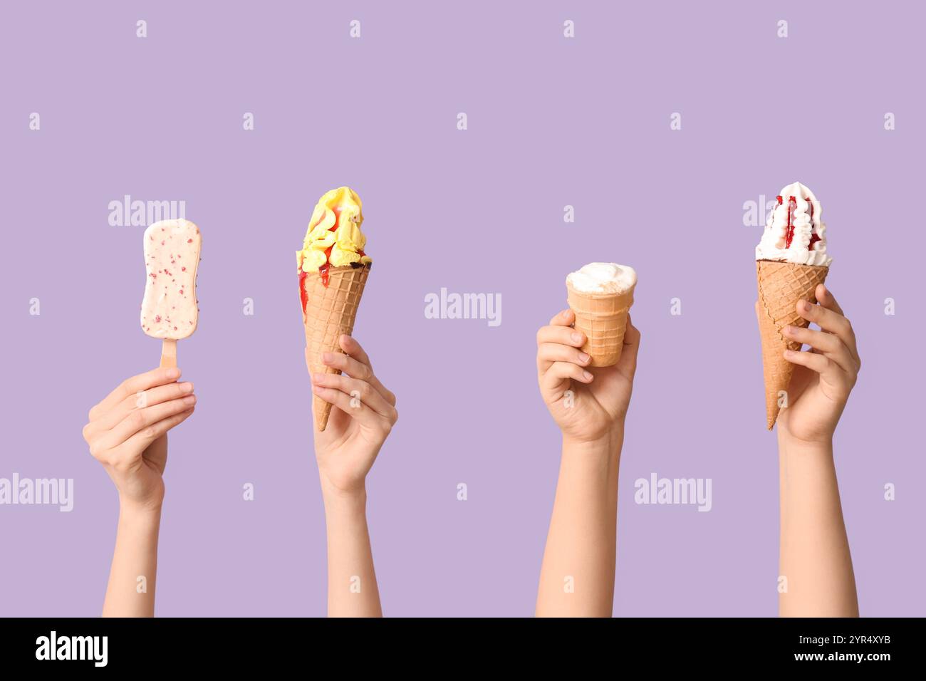 Mains féminines avec différentes glaces sucrées sur fond lilas Banque D'Images
