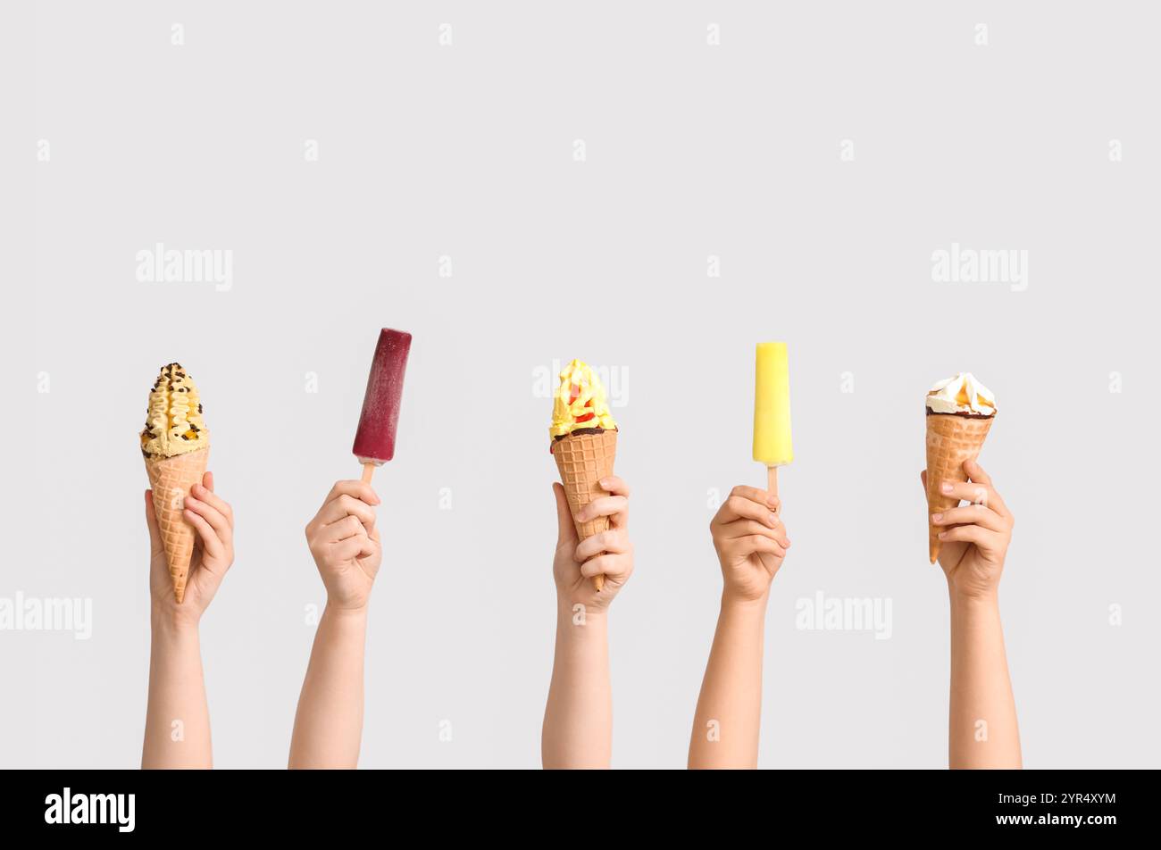 Mains féminines avec différentes glaces sucrées sur fond gris Banque D'Images