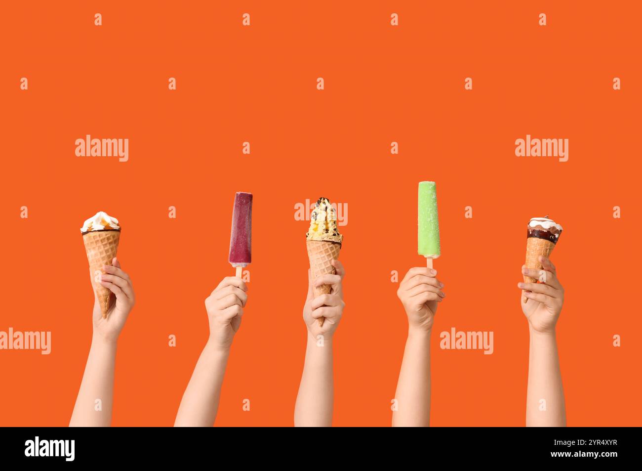 Mains féminines avec différentes glaces sucrées sur fond orange Banque D'Images