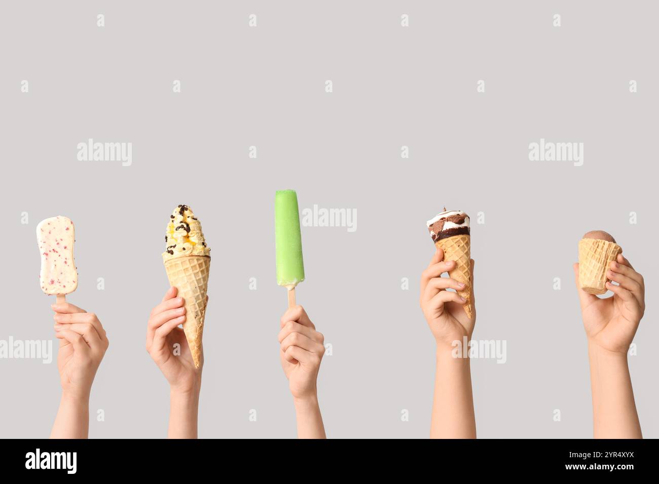 Mains féminines avec différentes glaces sucrées sur fond gris Banque D'Images