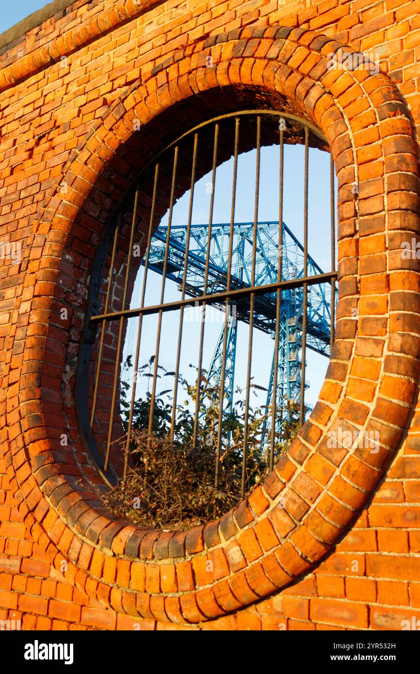 Vieux mur de briques rouges vulcan Salt fonctionne avec des ouvertures circulaires et un grand pont transporteur bleu visible en arrière-plan middlesbrough Teesside UK Banque D'Images