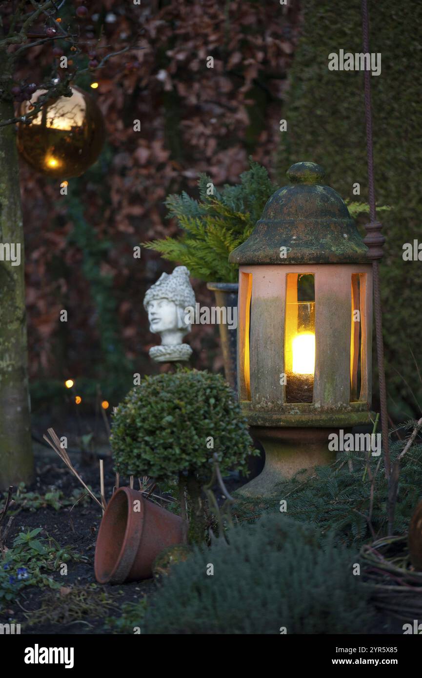 Lanterne de jardin et buste antique entre les plantes dans la lumière du soir, borken, muensterland, allemagne Banque D'Images