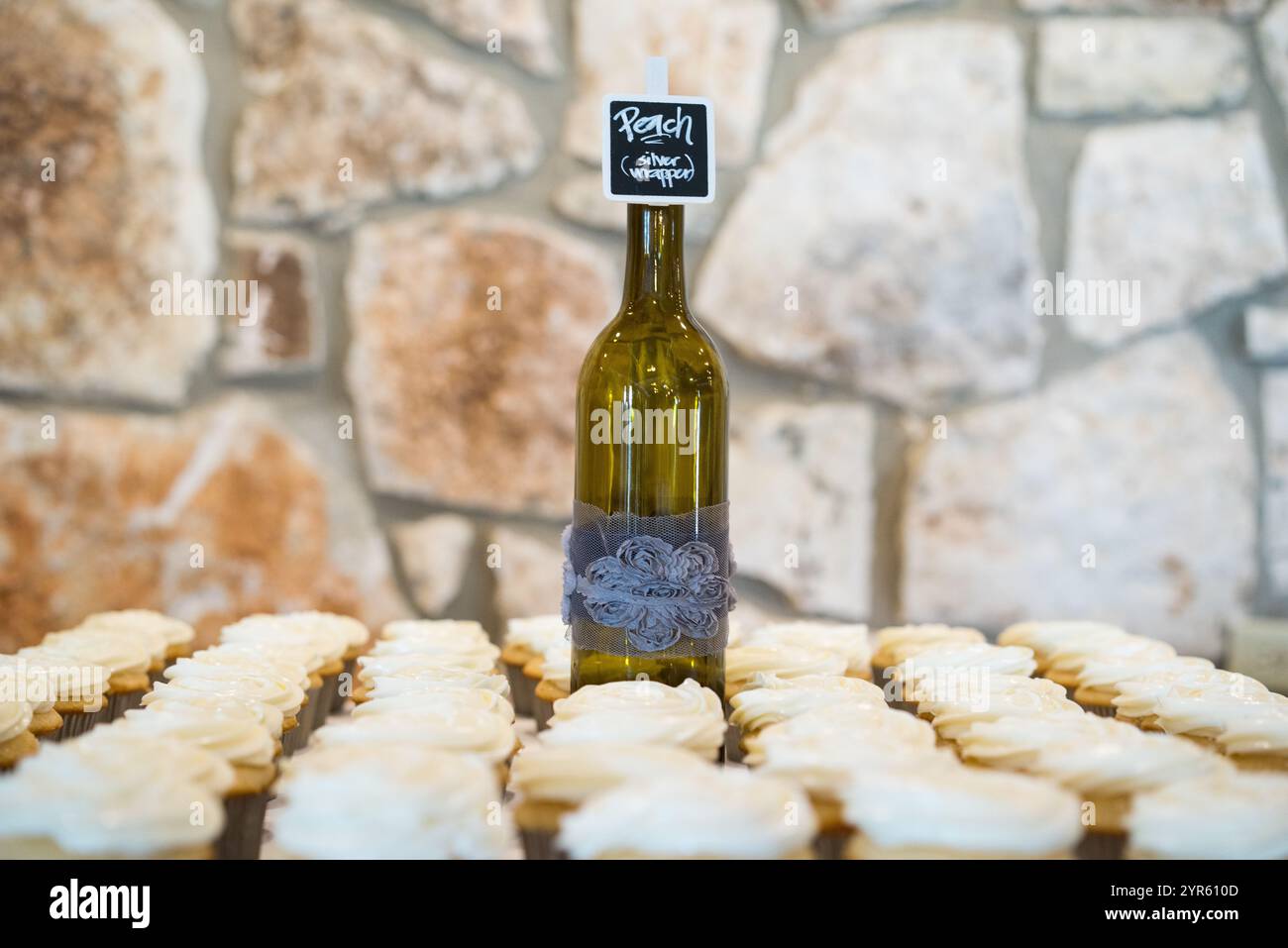 Pièce maîtresse de bouteille de vin avec des Cupcakes givrés sur fond rustique Banque D'Images