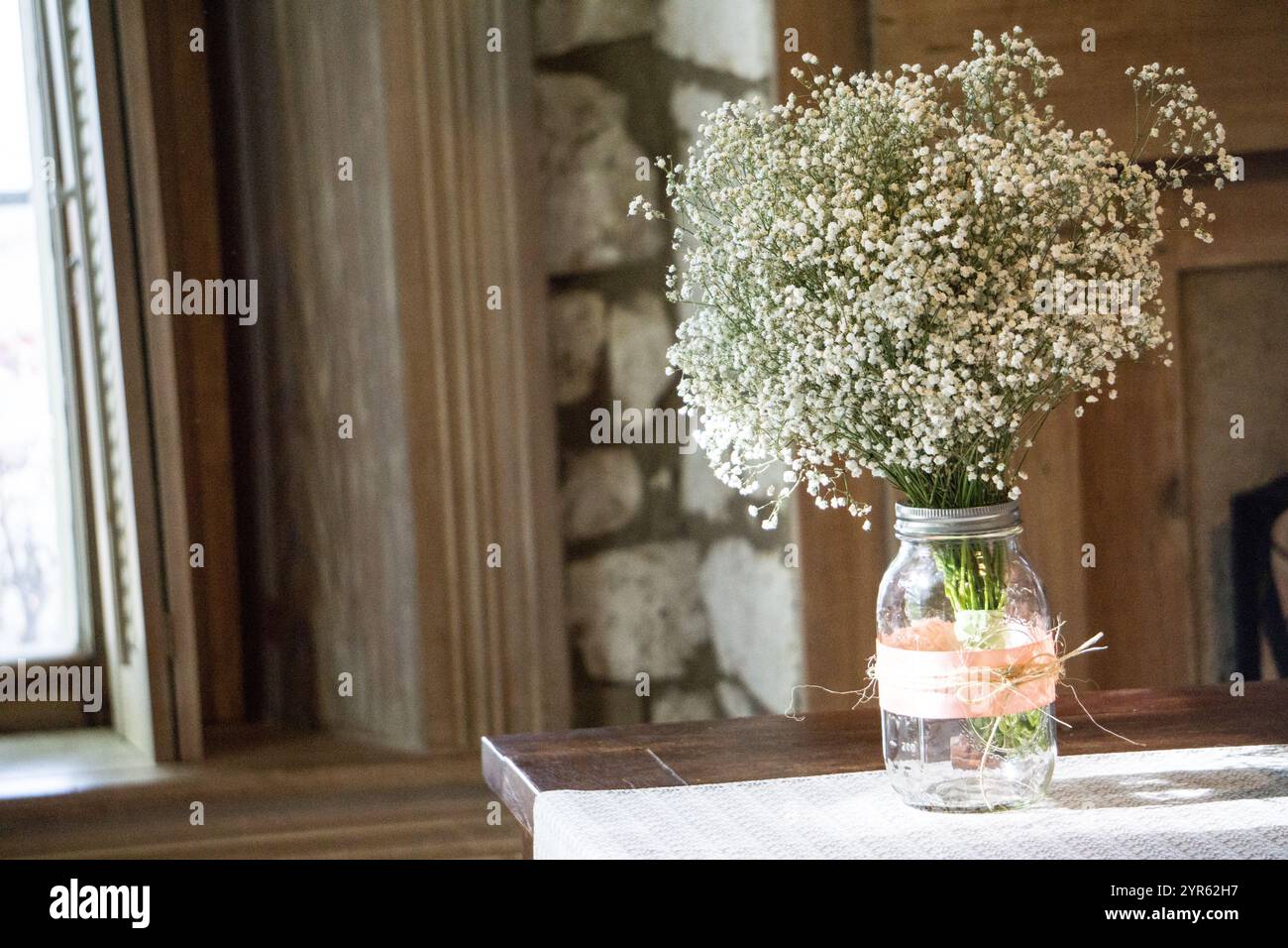 Bouquet de respiration de bébé rustique dans Mason Jar par fenêtre ensoleillée Banque D'Images