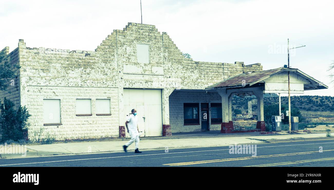 JUILLET, ARIZONA, États-Unis - Station d'essence fermée à distance le long de l'ancienne route 66 en Arizona montre un homme masqué COVID traversant la rue Banque D'Images